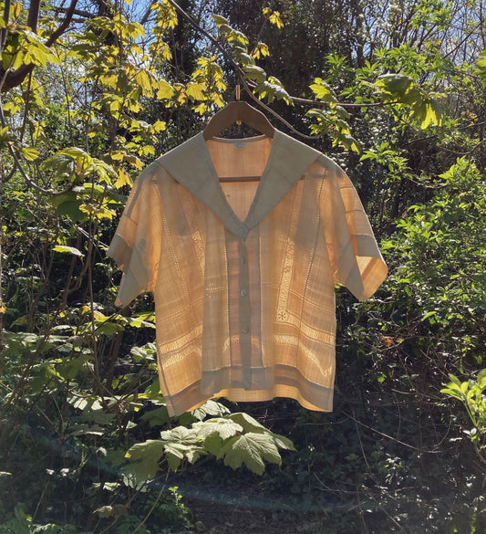 Sailor-collar shirt hand sewn from a reclaimed silk tablecloth, based on a vintage 80s pattern. Light and airy, cutwork detailing, fastens with found shell buttons. Shown hanging in a tree in dappled sunlight