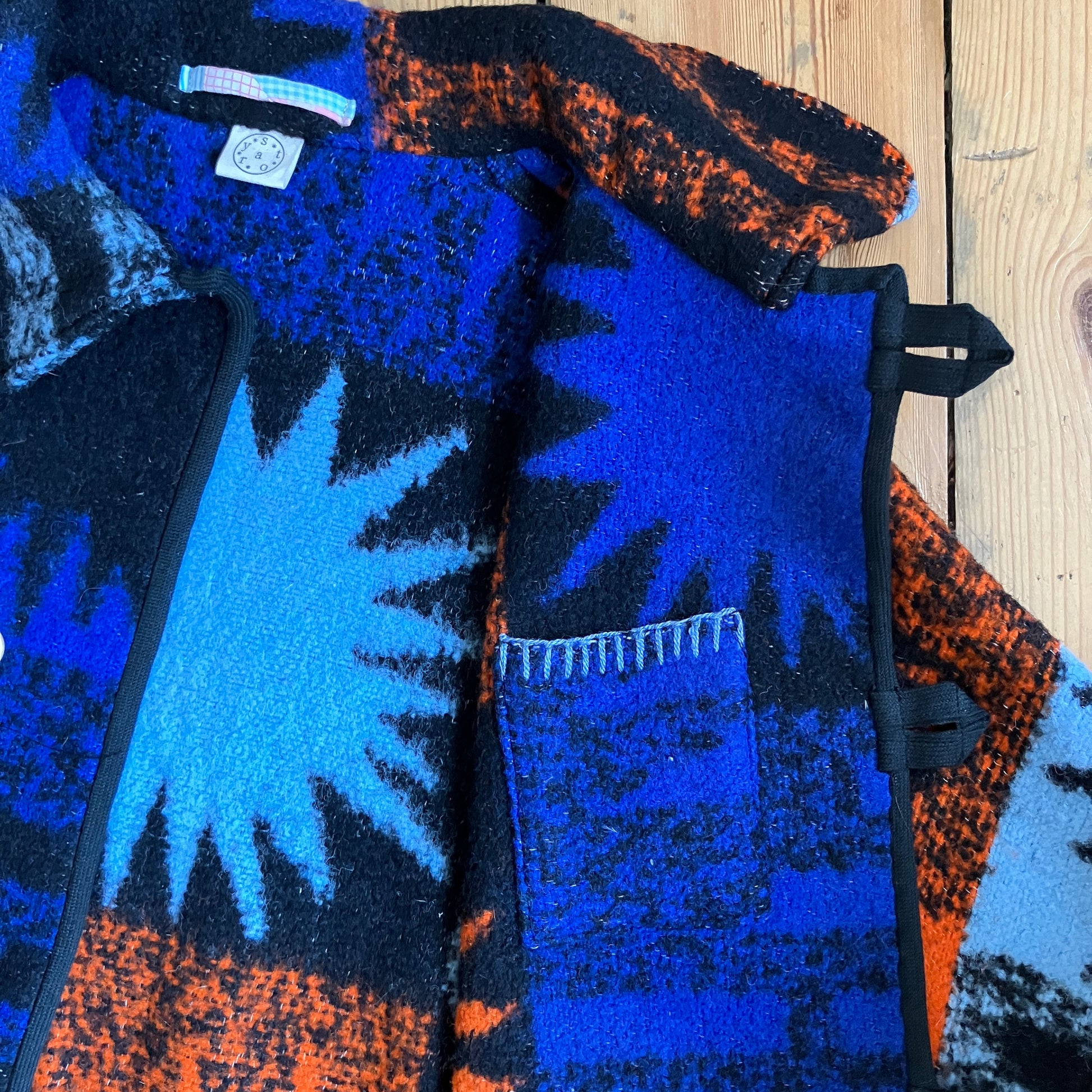 Crop-sleeved jacket made from a fabulous reclaimed blanket with starburst motifs in bright blue, light blue, black and orange (close-up of inside pocket)